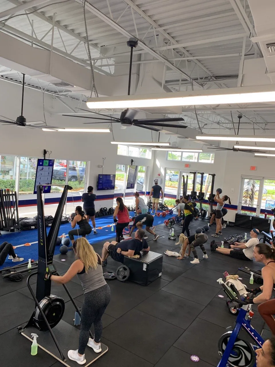 Full F45 Cooper City class training on the studio floor — rowers, box jumps, med balls